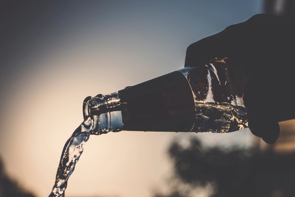 Water poured from a bottle into a glass at dusk